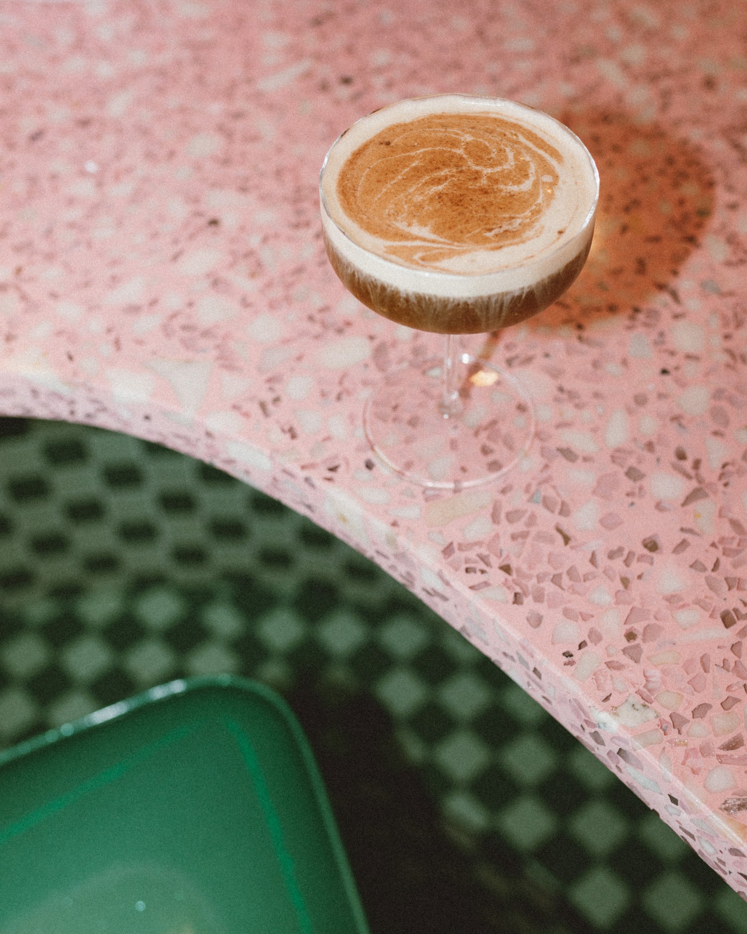 martini style glass at the edge of the bar, filled to the brim with a delicious latte