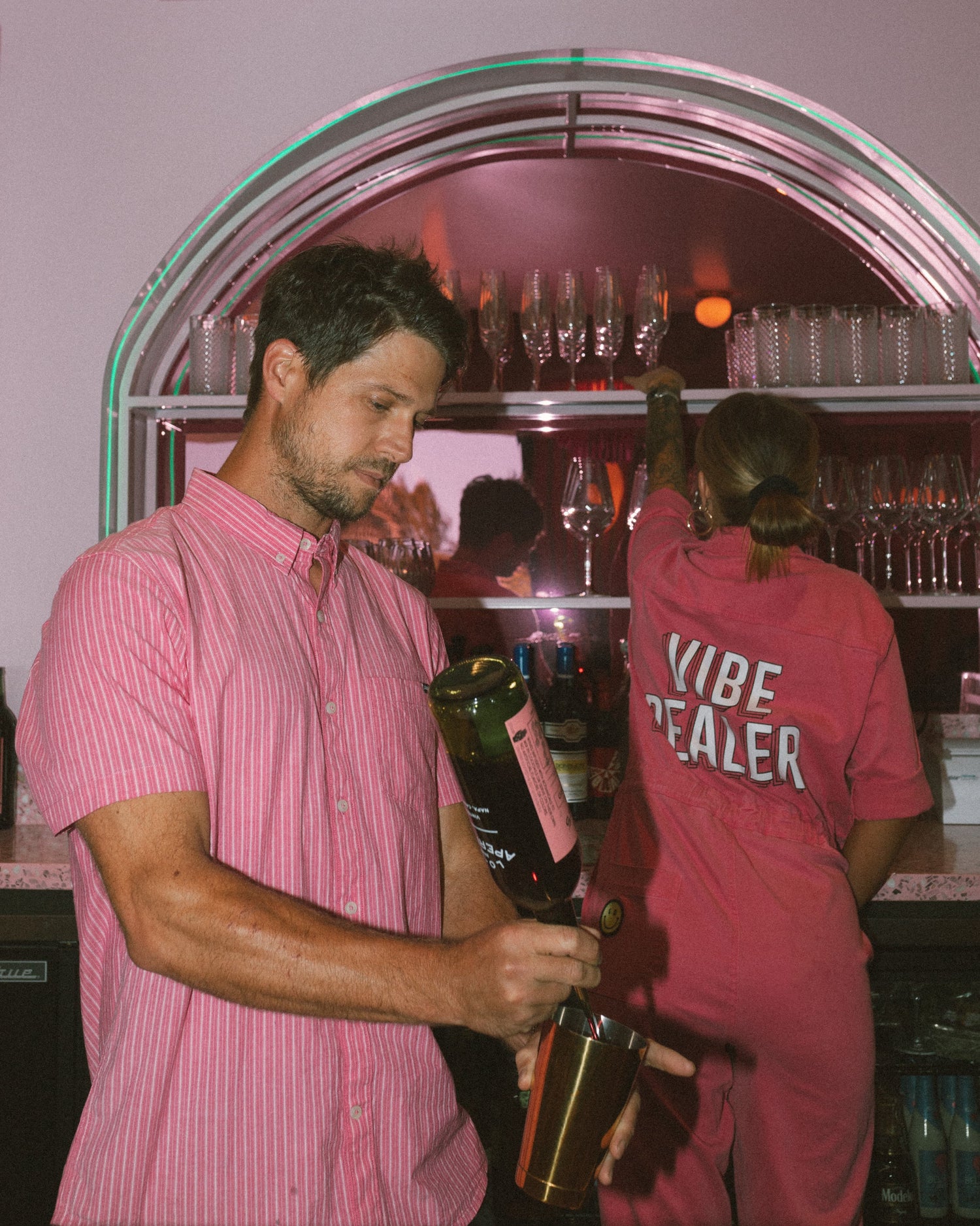 vibe dealers in pink, about to serve up a drink and grabbing a glass