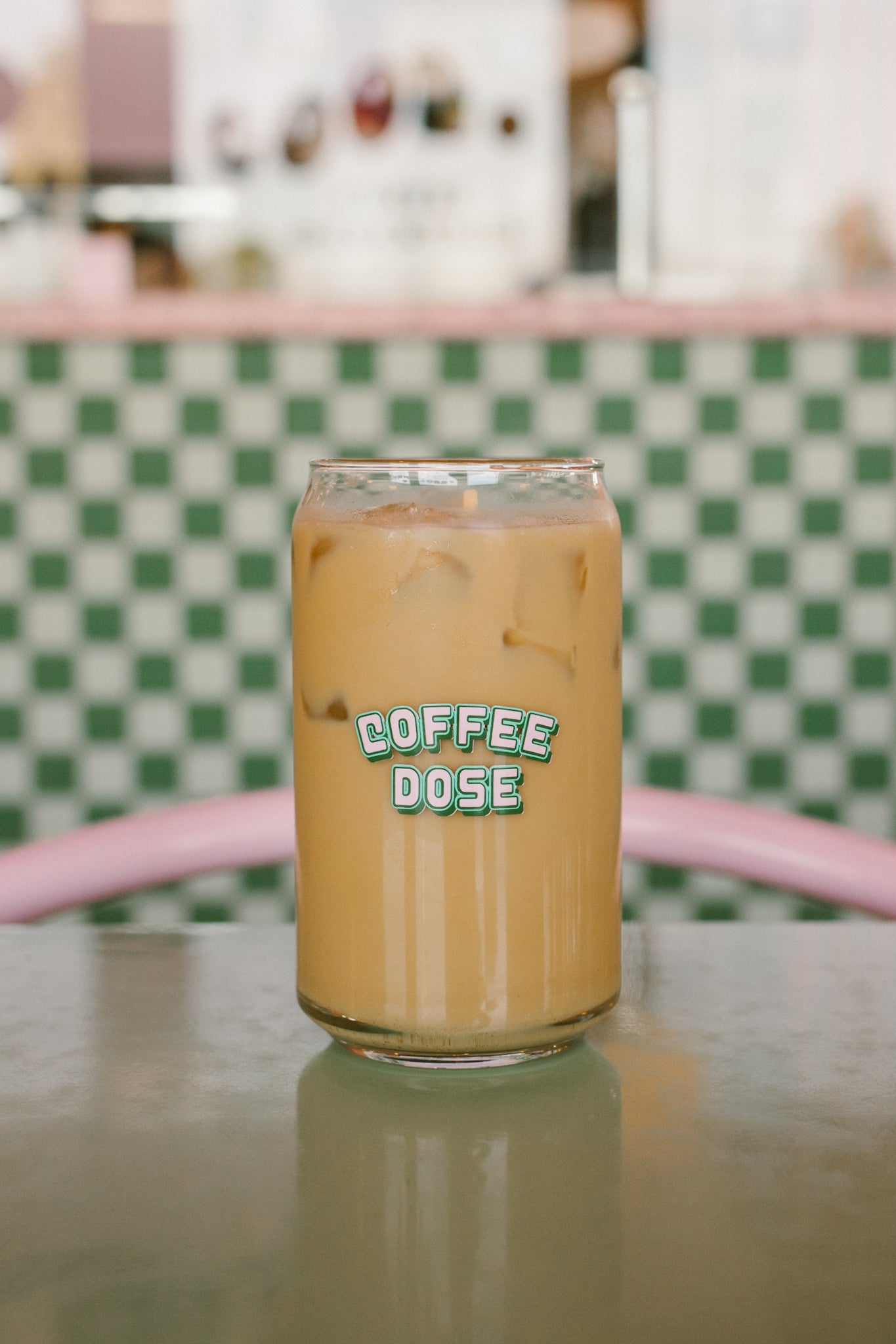 Glass of iced coffee with 'Coffee Dose' label on a checkered tablecloth.