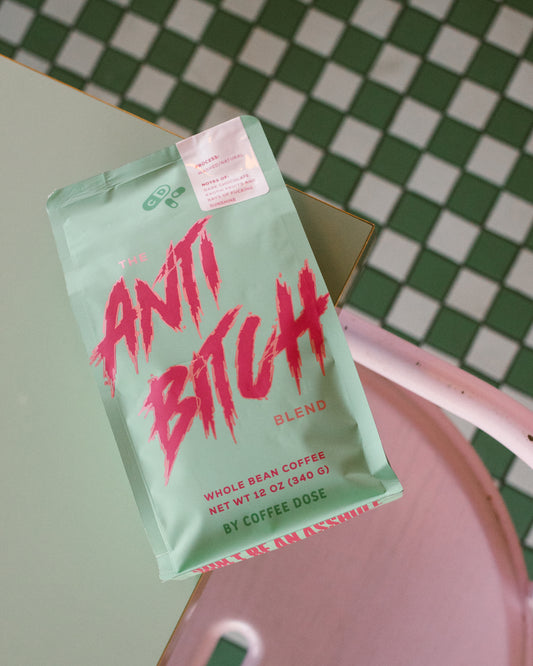 Coffee bag labeled 'Anti Bitch Blend' on a table beside checkered floor