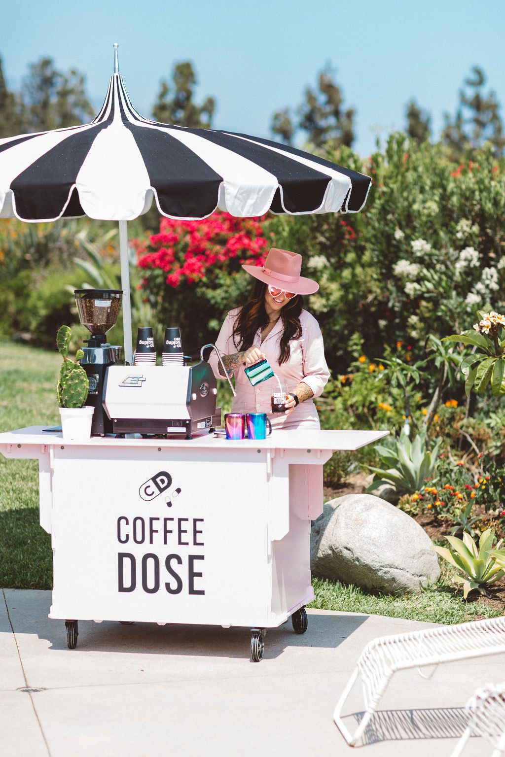 coffee stand with vibe dealer pouring steamed milk into a coffee beside a pool area