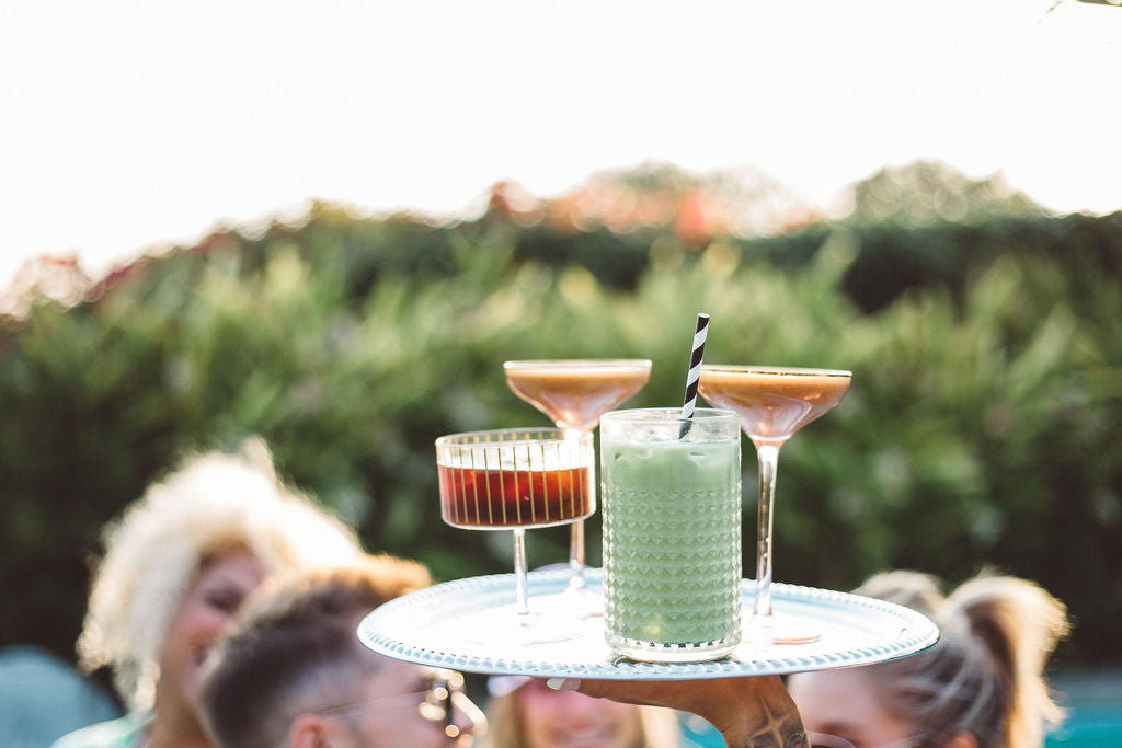 holding up platter of coffee drinks beside the pool